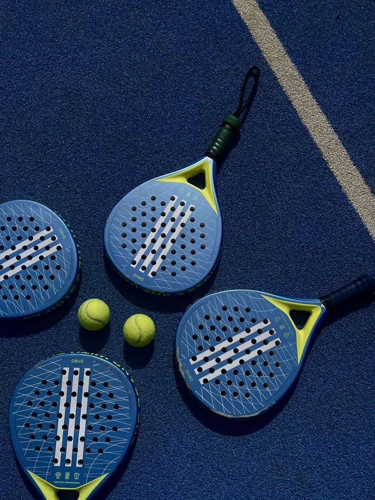 Palas de p&aacute;del y pelotas sobre pista azul