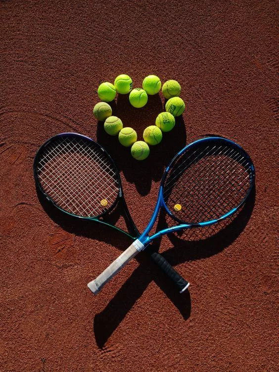 Raquetas y pelotas de tenis sobre tierra batida